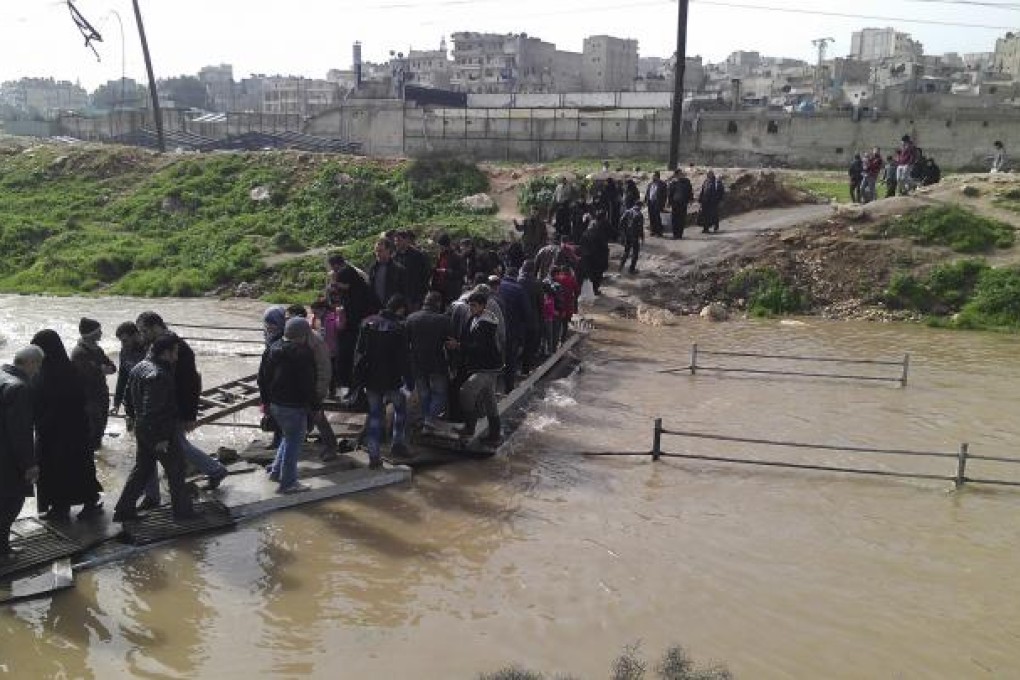 People cross a makeshift bridge between the Sheikh Maksoud and Bustan al-Basha districts of Aleppo. Photo: Reuters