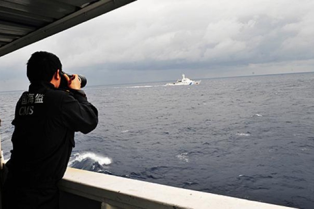 A China Marine Surveillance officer photographs a Japan Coast Guard vessel near the disputed Diayou Islands last week. Photo: Xinhua