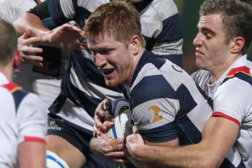 Hong Kong Football Club's Rob McDermott is tackled by HKCC's Tom Marshall yesterday. Photo: KY Cheng