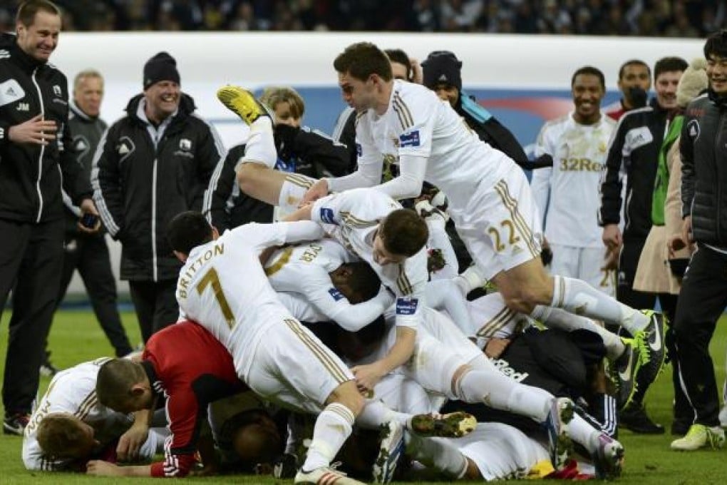 Swansea City players celebrate by piling on top of each other after defeating Bradford City 5-0 in the English League Cup final at Wembley Stadium on Sunday. Photo: Reuters