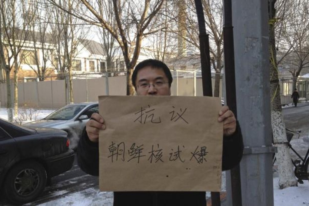 A protester holding a sign poses for a photo outside the North Korea consulate in Shenyang. Photo: Reuters