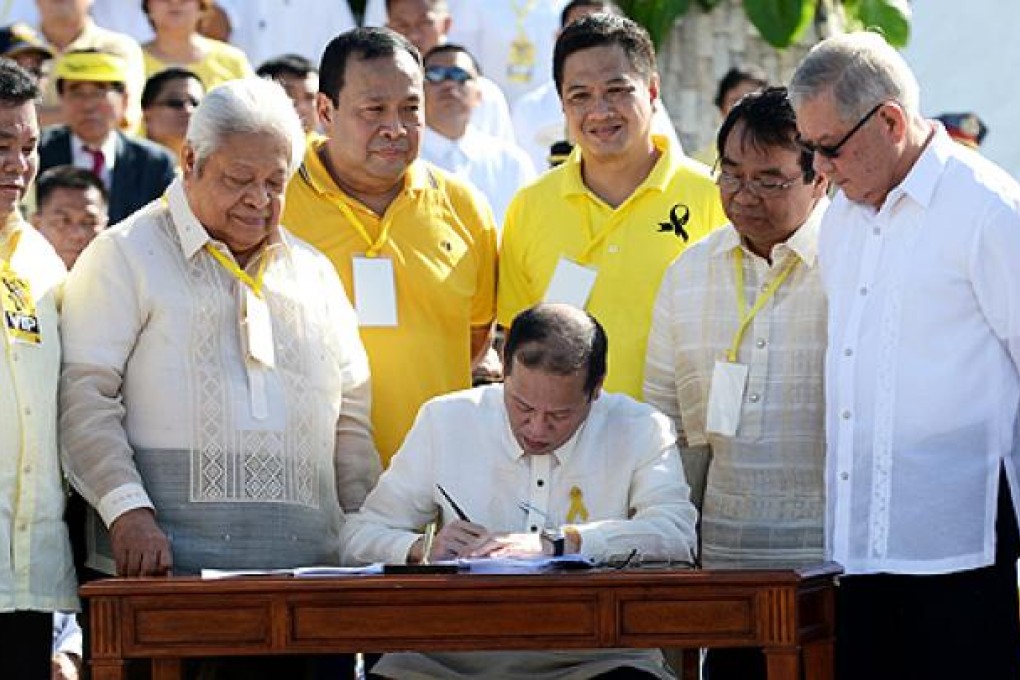 Philippine President Benigno Aquino (centre) signs the Martial Law Compensation bill during the 27th anniversary of the People Power revolution at the People Power monument in Manila on Monday. Photo: AFP
