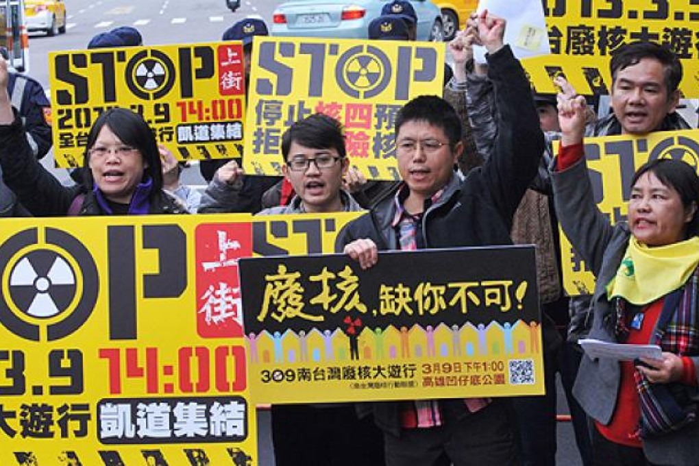 Members of environmental groups hold placards and chant slogans as they attend an anti nuclear plant protest in front of the presidential office in Taipei on February 21. Photo: AFP