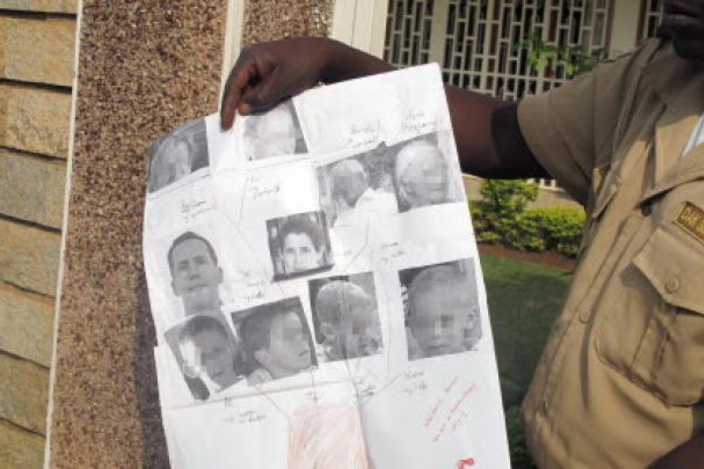 A security guard shows photos of Tanguy Moulin-Fournier and wife Albane (centre) and their four children, kidnapped this month while visiting the Waza National Park.. Photo: AFP