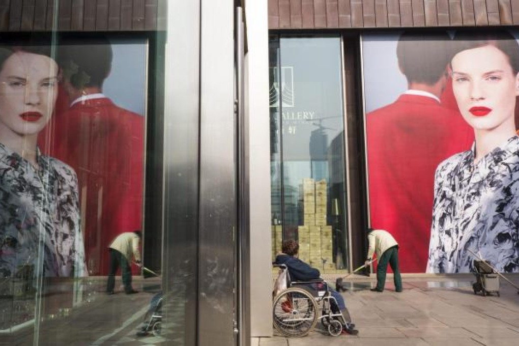 A cleaner toils outside an upmarket shopping centre in Beijing. Three decades of rapid economic growth have seen income inequality widen dramatically on the mainland, presenting an acute challenge for the incoming leadership. Photo: EPA