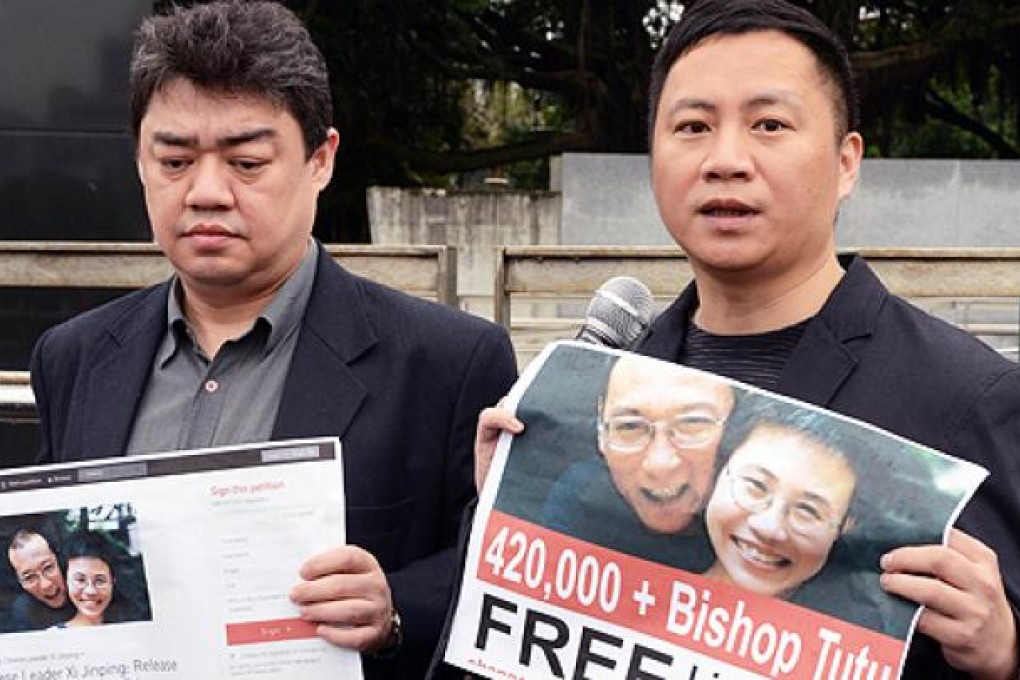 Wang Dan (right) and Wuer Kaixi hold posters in front of Taiwan's presidential office calling Taiwan's President Ma Ying-jeou to help to free China's jailed Nobel laureate Liu Xiaobo, in Taipei on Wednesday. Photo: AFP