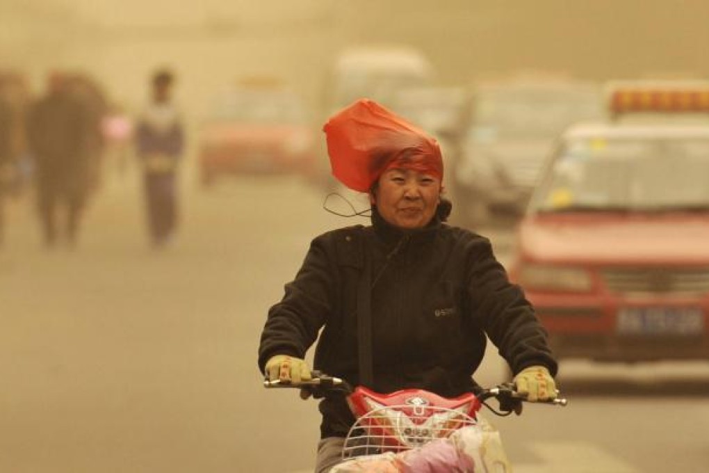 A woman wears a plastic bag to keep the dust out of her hair in Taiyuan yesterday. Photo: Reuters