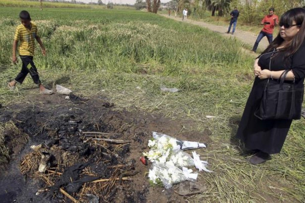 A Japanese tourist places flowers at the wreckage of a hot air balloon that crashed in Luxor. Photo: Reuters