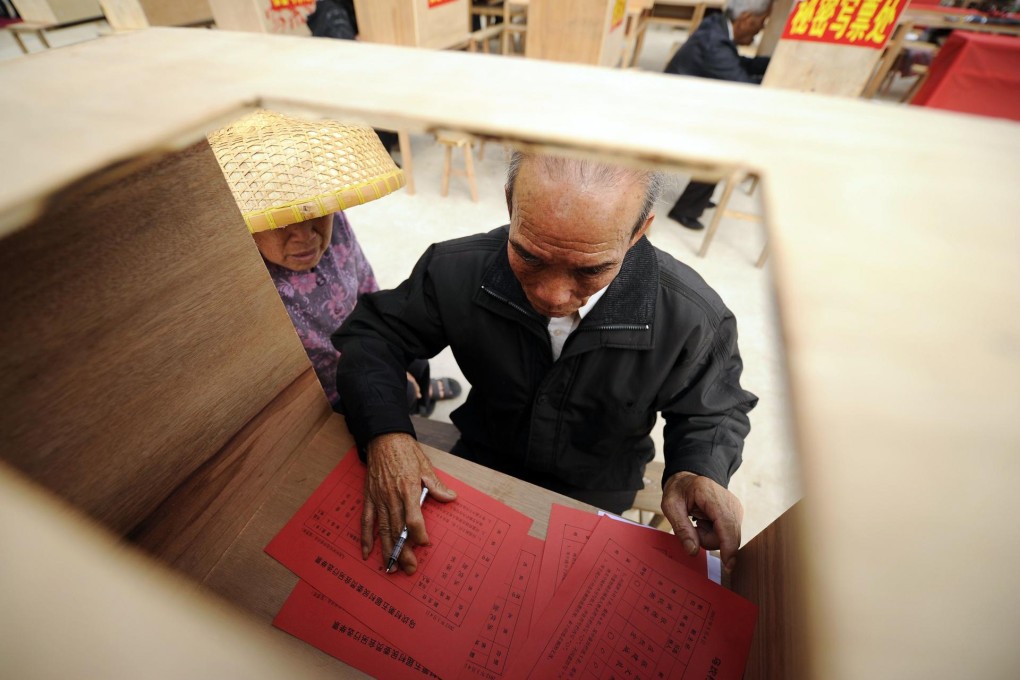 A woman watches her husband fill out his ballot paper in the remote Guangdong fishing village of Wukan in March last year. Photo: AFP