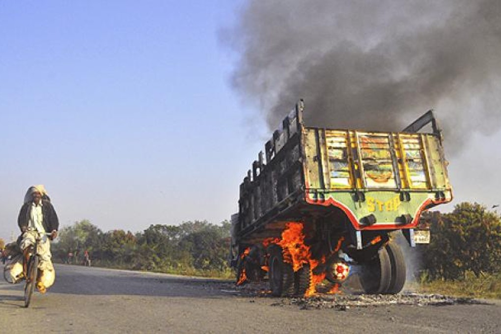 A Bangladeshi man rides past a truck set on fire by activists of Islamic party Jamaat-e-Islami during a strike called by the party in Rajshahi, Bangladesh. Photo: AP