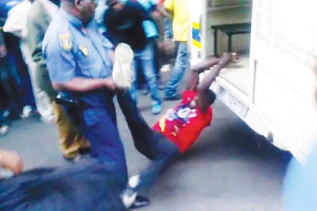 A still from a video made available by The Daily Sun shows Mido Macia, 27, a taxi driver and Mozambican national, as he is dragged behind a police van while police officers watch, in Johannesburg. Photo: EPA