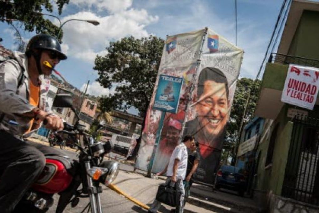 People crosses in front of a billboard showing Venezuelan President Hugo Chavez, outsides the Military Hospital in Caracas. Photo: EPA
