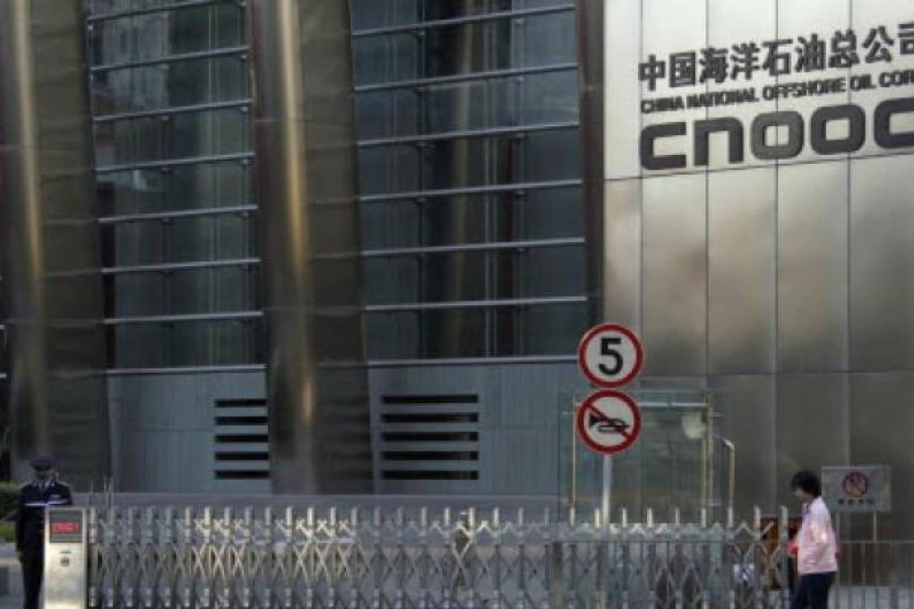 A woman walks past the entrance of the headquarters of China National Offshore Oil Corp (CNOOC) in Beijing. Photo: Reuters