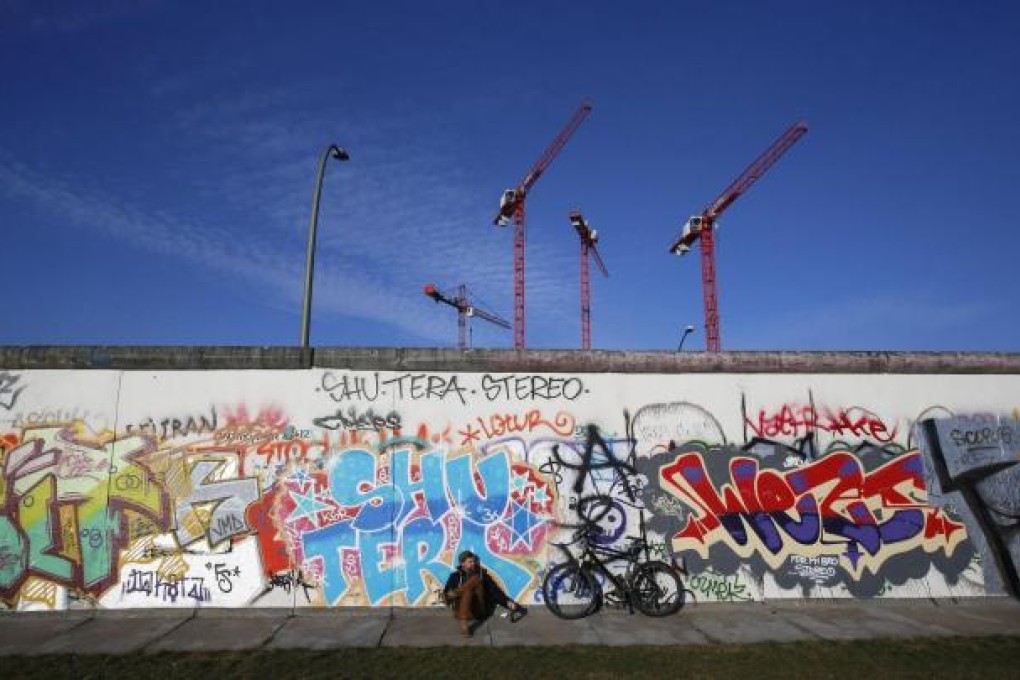 A man takes a rest against the open-air section of the Berlin Wall known as the East Side Gallery, which stretches for 1.3km. Photo: Reuters