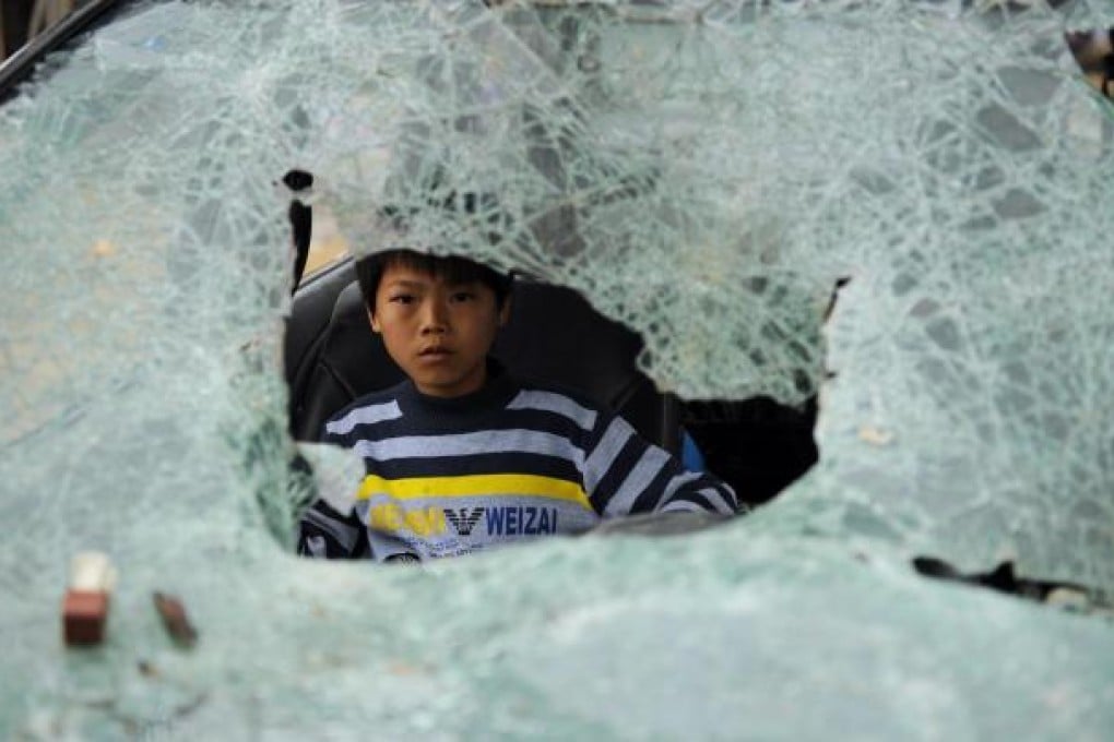 A boy plays in a damaged vehicle. Photo: AFP