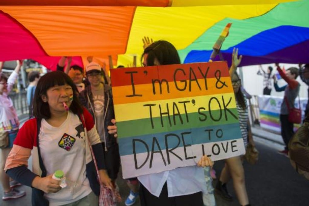 Demonstrators walk under a giant rainbow flag and chant slogans during a gay pride parade in Hong Kong on November 10, 2012. Photo: EPA