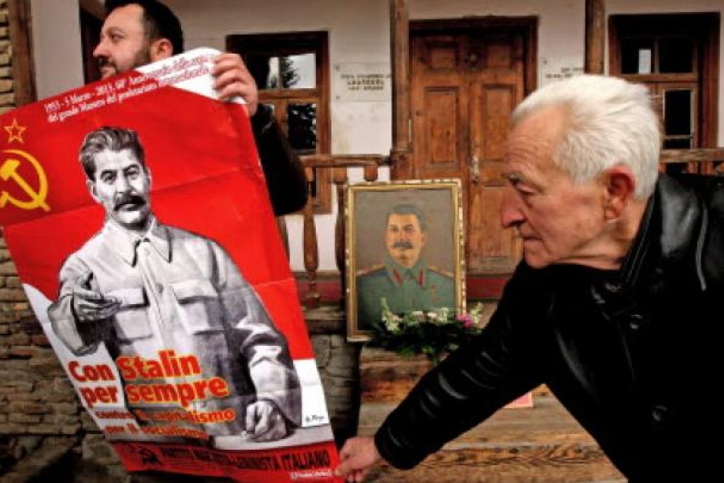 Two Georgian men hold a portrait of Soviet dictator Joseph Stalin as they mark the 60th anniversary of Stalin's death. Photo: EPA