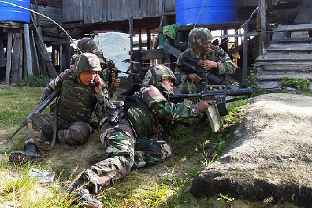 Malaysian soldiers move into Kampung Tanduo, where troops stormed the camp of an armed Filipino group in Sabah. Photo: Reuters
