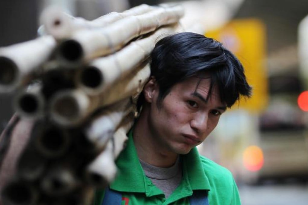 Shouldering the frame: Scaffolder Anson Yan, 31, carries a supply of bamboo rods. Photo: Nora Tam