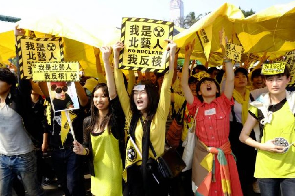 Young women wave placards and shout slogans denouncing nuclear energy during the huge protest in Taipei yesterday. Photo: AP