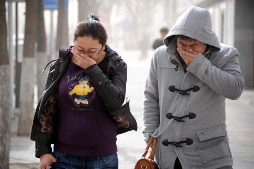 Pedestrians shield their mouths as sand, dust and dry winds sweep Beijing. Photo: Xinhua