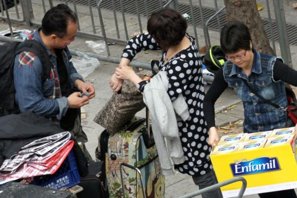 People repackage milk powders into smaller luggages outside Sheung Shui train station. Photo: Nora Tam