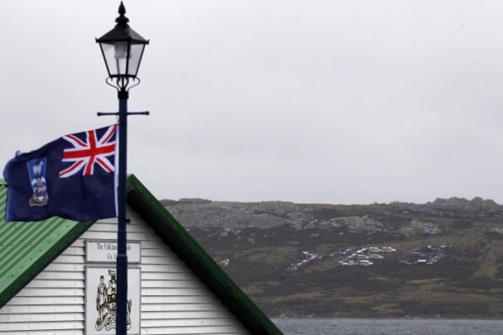 A Falkland Islands' flag waves as a "Yes" sign formed with cars is seen on a hill in Stanley. Photo: Reuters