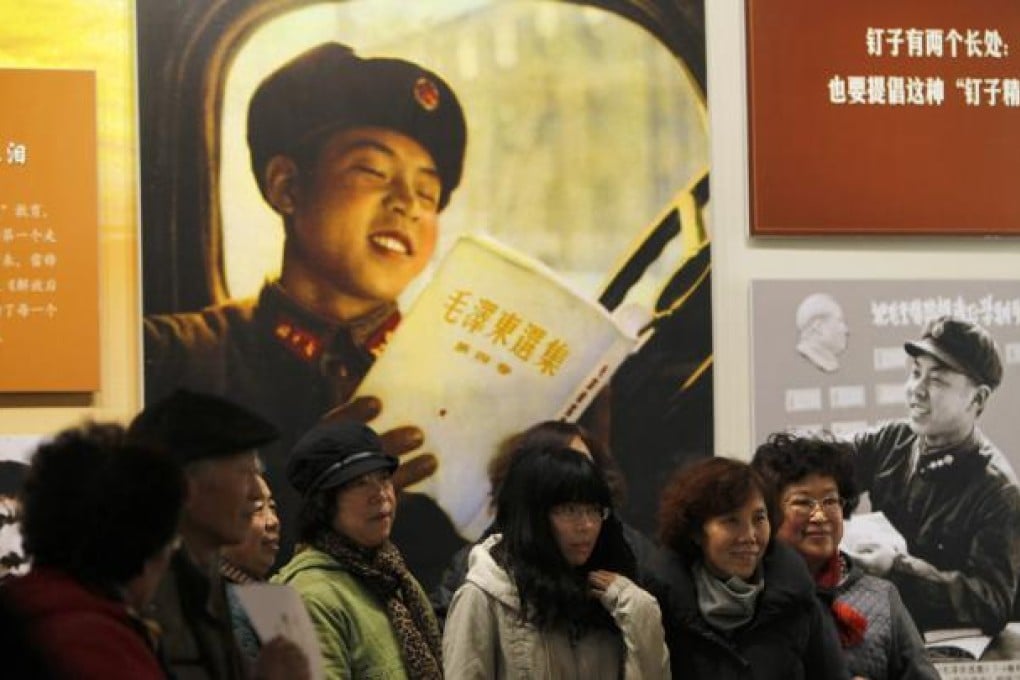 Visitors pose in front of large photos of Lei Feng in an exhibition commemorating the 50th anniversary of 'Learn from Lei Feng Day' at the Beijing World Art Museum. Photo: EPA