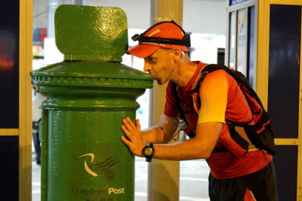 Andre Blumberg kisses the finishing marker of the Hong Kong Four Trails Ultra Challenge after running 298km in three days. Photo: Patchanida Pongsubkarun