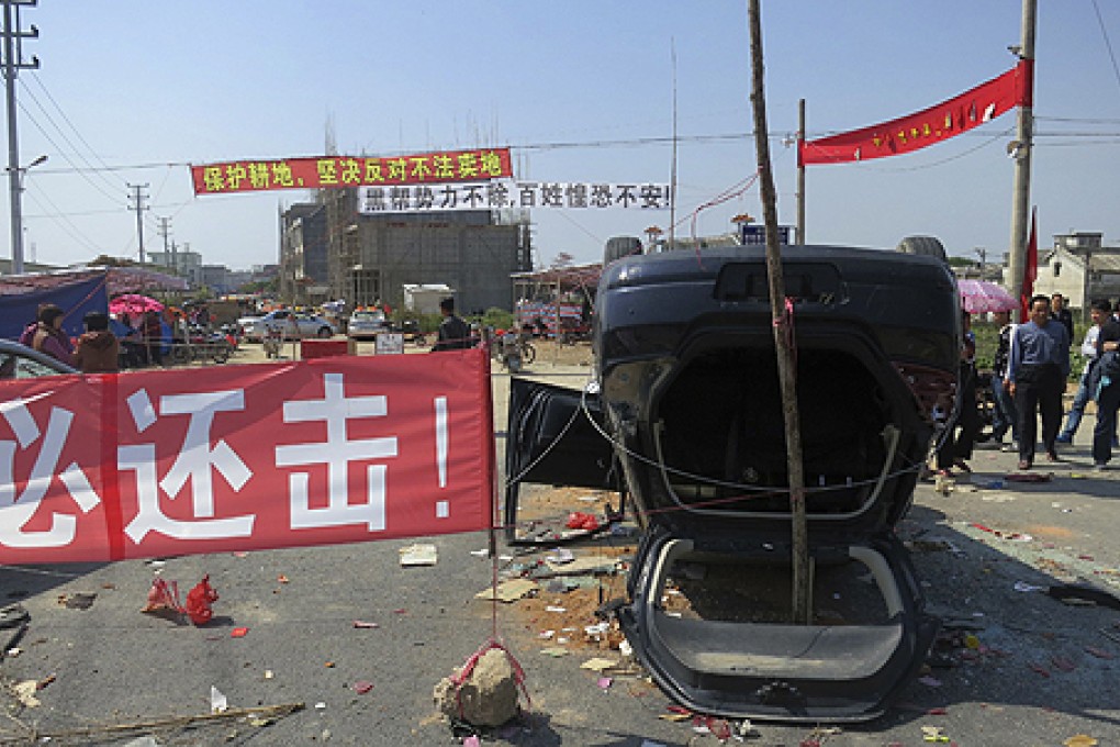 A red sign reading "We must retaliate" is next to an upended car at the entrance of Shangpu village in Guangdong province last week. Photo: Reuters