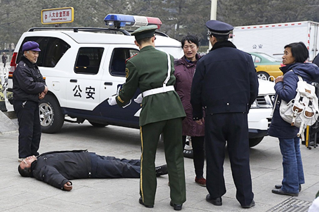 Police ask a petitioner to get up as he lies on the ground in an effort to draw attention outside the Great Hall of the People last week. Photo: Reuters