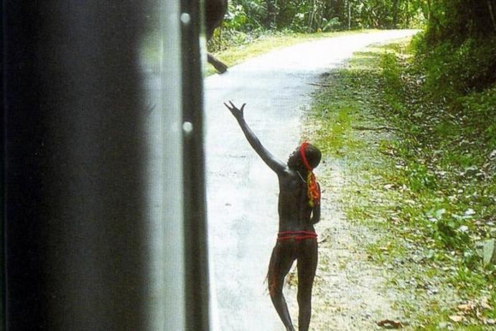 A Jarawa tribesman seeks handouts from a bus on the Andaman Trunk Road, which is due to officially reopen. Photo: AFP