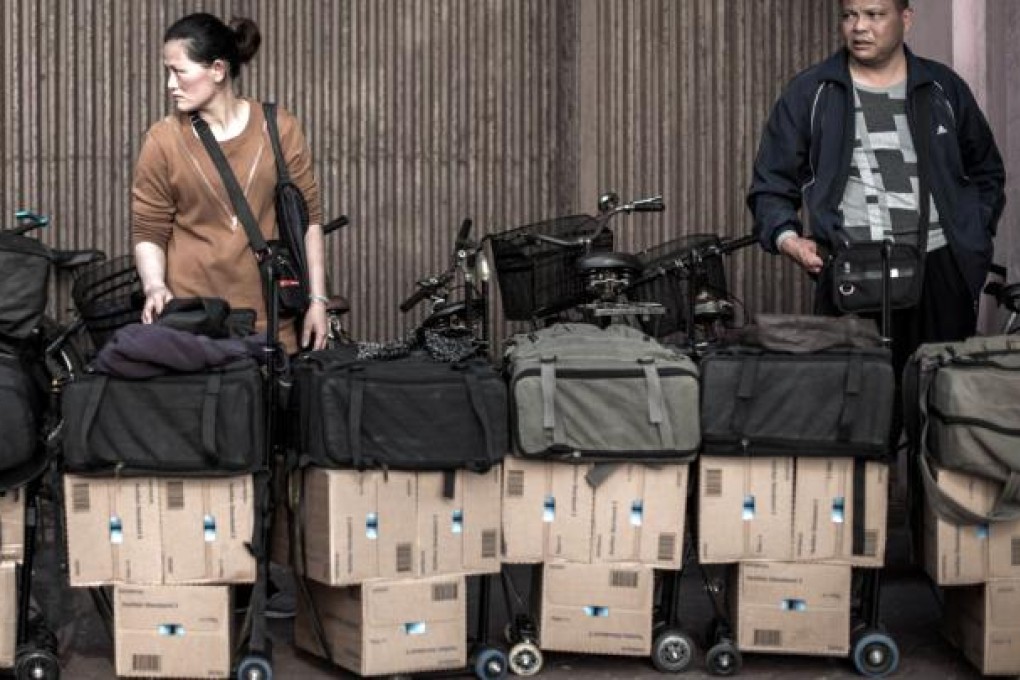 A woman waits near boxes of mainland-bound baby formula in the queue to get packages weighed at Sheung Shui station. Photo: AFP