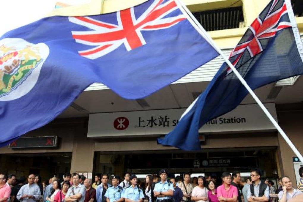 Protestors wave Hong Kong colonial flags outside Sheung Shui MTR station.