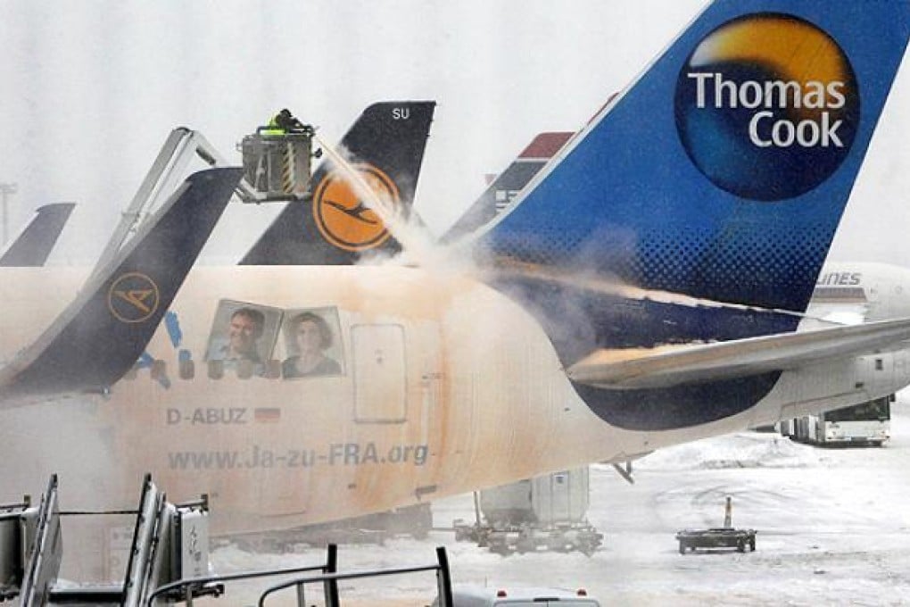 Airport workers de-ice a plane on the snow-covered tarmac of Frankfurt airport. Photo: AFP