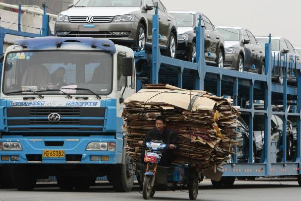 A man rides an electric tricycle past a truck loaded with new Volkswagen cars on a street in Nanjing. Photo: Reuters