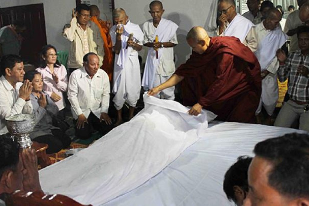 Ieng Vuth (left), son of Ieng Sary, prays with his family near the body of his father at their home in former stronghold of Malai near the Cambodian-Thai border. Photo: AP