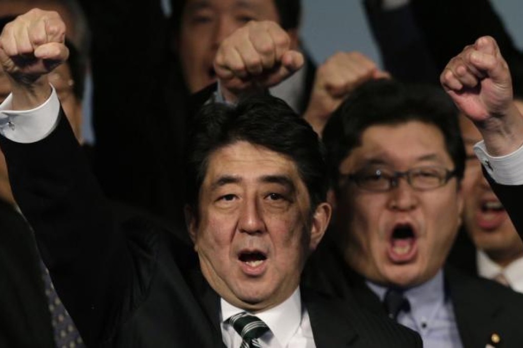 Shinzo Abe salutes with a closed fist along with other members of the Liberal Democratic Party at a party meeting yesterday. Photo: Reuters