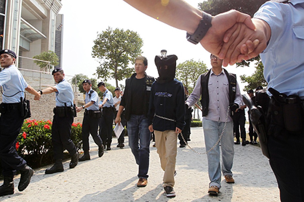Police escort a murder suspect on Saturday in the case of a dismembered elderly couple in Tai Kok Tsui. Photo: Felix Wong