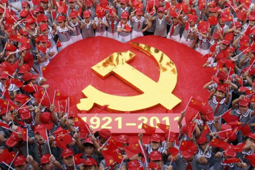 Students wave flags of the Communist Party of China as they pose for a photo with an emblem of the CPC at a primary school. Photo: Reuters