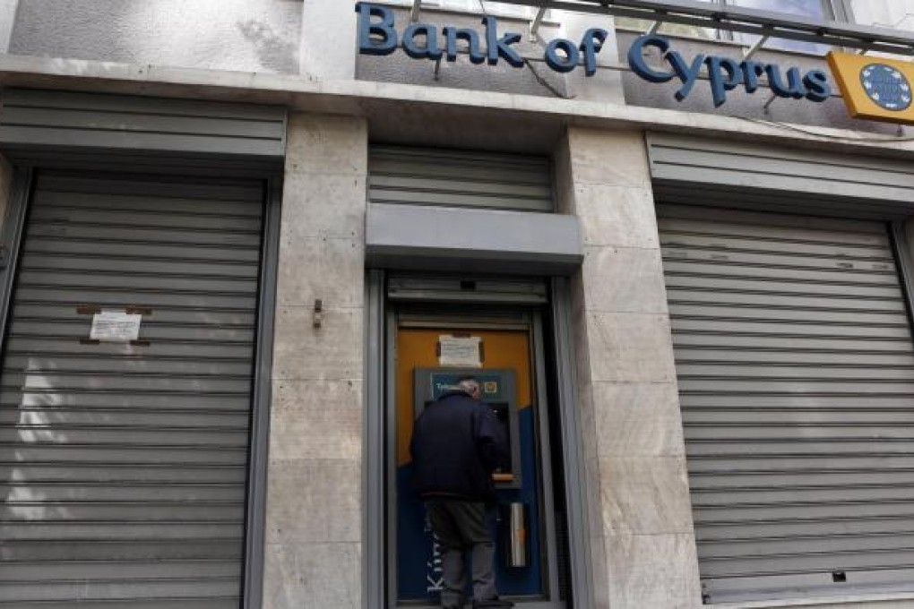 A customer of the Bank of Cyprus carries out a transaction at an ATM machine outside a branch in Athens. Greek branches of Cypriot banks will remain shut today, in line with Nicosia's plan for a two-day bank holiday. Photo: Reuters