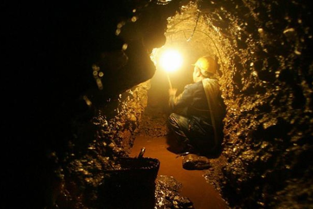 A worker digs for gold in a pit in Qingmuchuan, northwest China. Photo: EPA