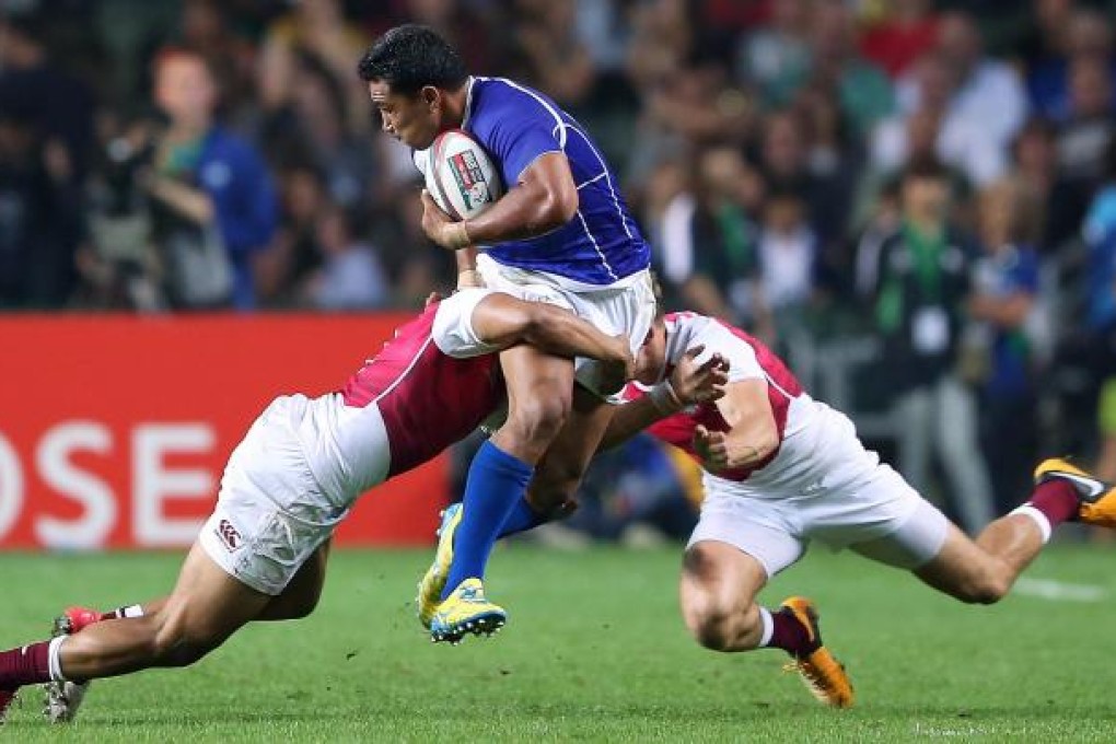 Samoa's Reupena Levasa takes two England defenders with him in last night's convincing victory at Hong Kong Stadium. Samoa shocked England 28-7. Photo: Felix Wong.
