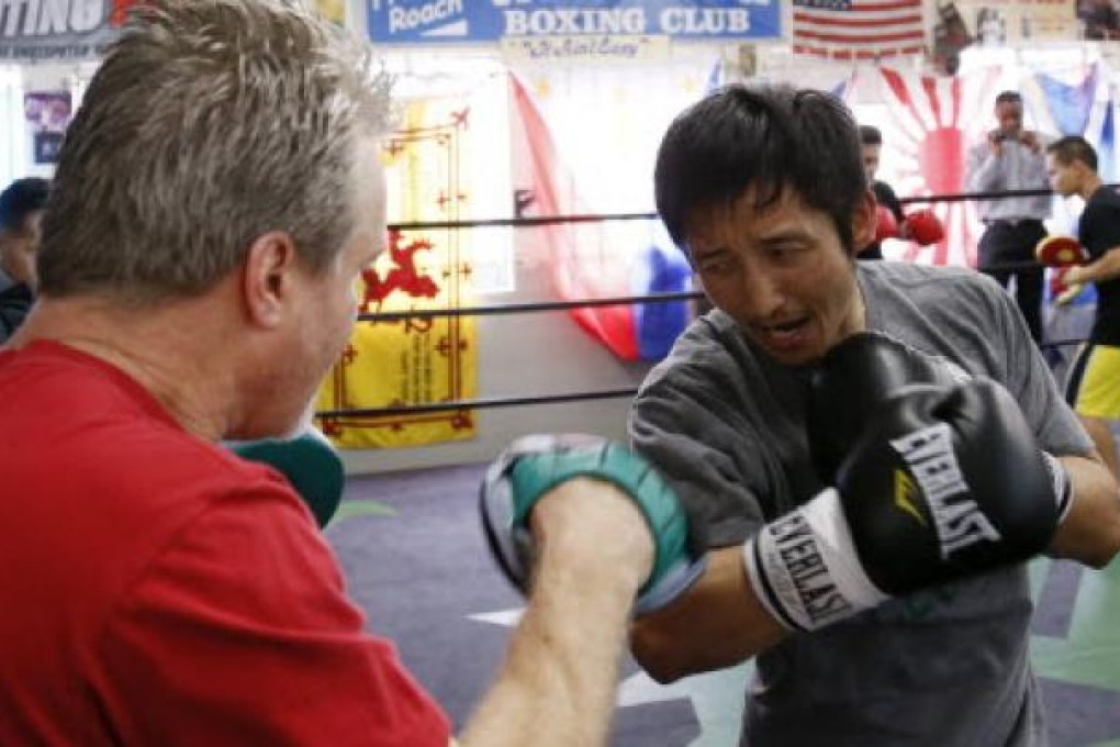 Two-time Olympic gold medalist and three-time world amateur boxing champion Zou Shiming of China works out with trainer Freddie Roach (left). Photo: Reuters