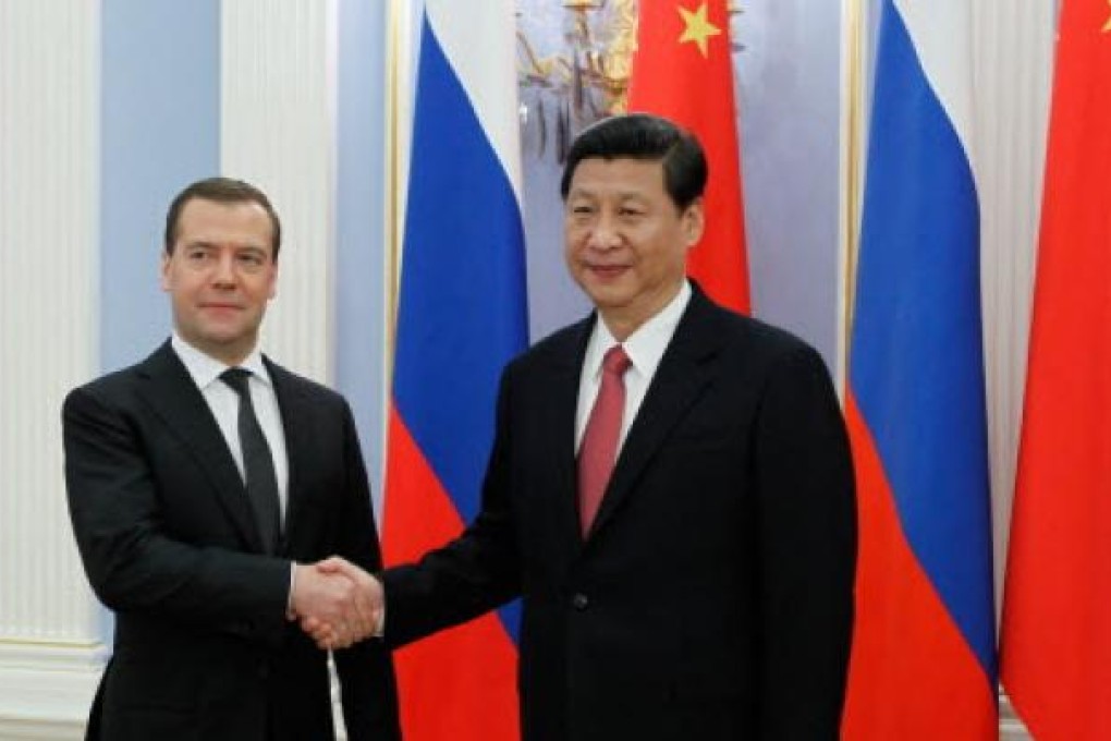 Russia's Prime Minister Dmitry Medvedev (left) shakes hands with China's President Xi Jinping (right) in Moscow on Saturday. Photo: EPA