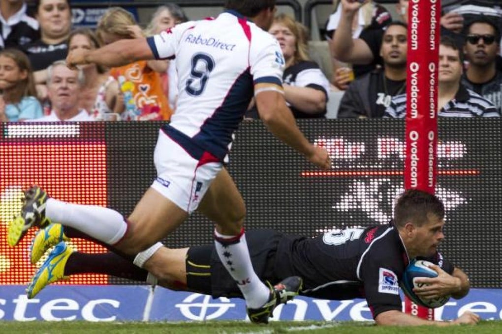 Louis Ludik of South Africa's Sharks dives over for a try with Melbourne Rebels' Gareth Delve helpless to stop him. Photo: Reuters