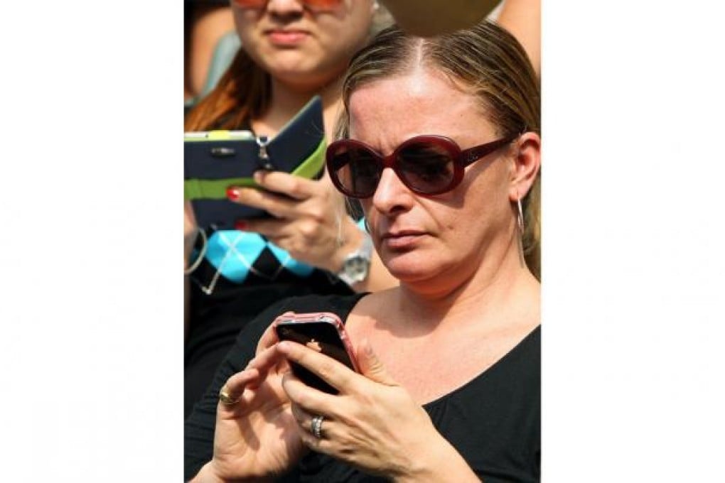 A spectator uses her mobile phone to send a text ... but will autocorrect spoil her day? Photo: Edmond So