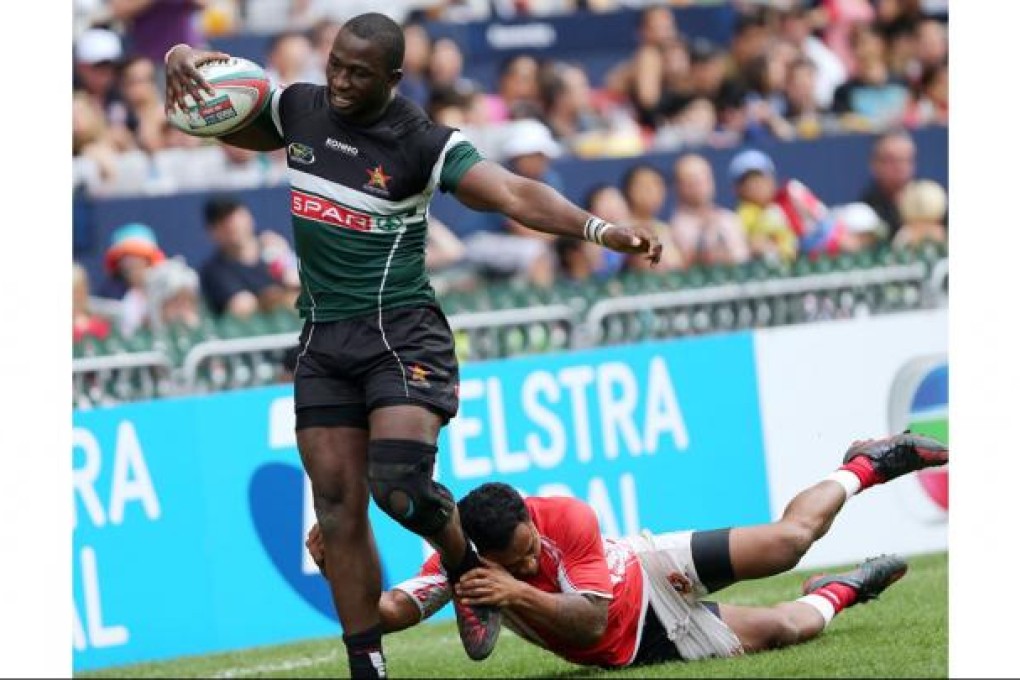 Tonga's Kilifa Latu clings grimly to the the sturdy legs of Zimbabwe's Njabulo Ndlovu in their pre-qualifier final. Photo: Sam Tsang