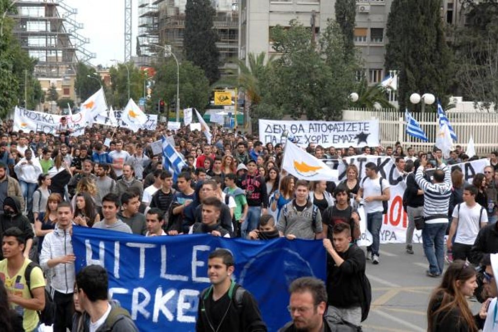 Cypriots take to the streets to protest the terms of the rescue package imposed by the European Union, the European Central Bank and the International Monetary Fund. The Cyprus bailout has sent shockwaves through global markets and fund managers are taking a more cautious stance. Photo: Xinhua