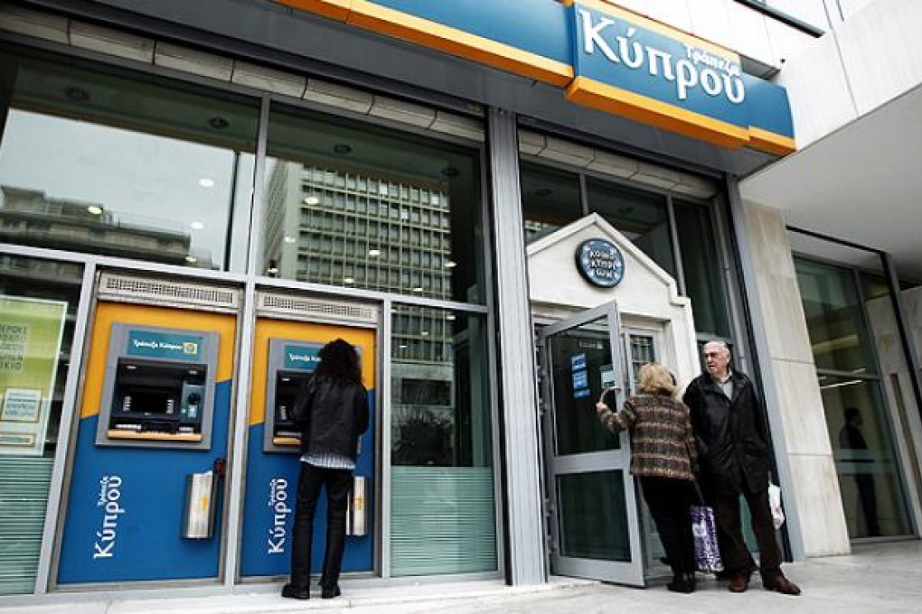 A man withdraws money from an ATM machine at the Bank of Cyprus headquarters in Athens, Greece. Photo: EPA